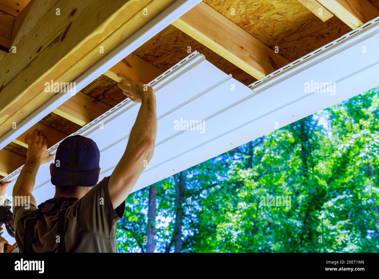 Having new employee install vinyl soffit plastic panels on facade