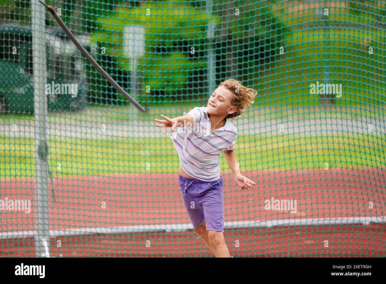 Javelin throw competition for kids. Athletics club training in school. Little boy throwing javelin on school stadium. Young athlete exercising. Stock Photo