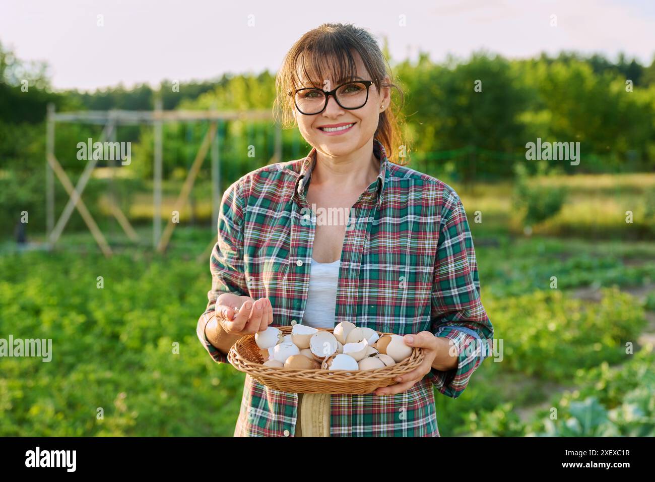 Woman with eggshell in wicker bowl, outdoor garden background Stock Photo