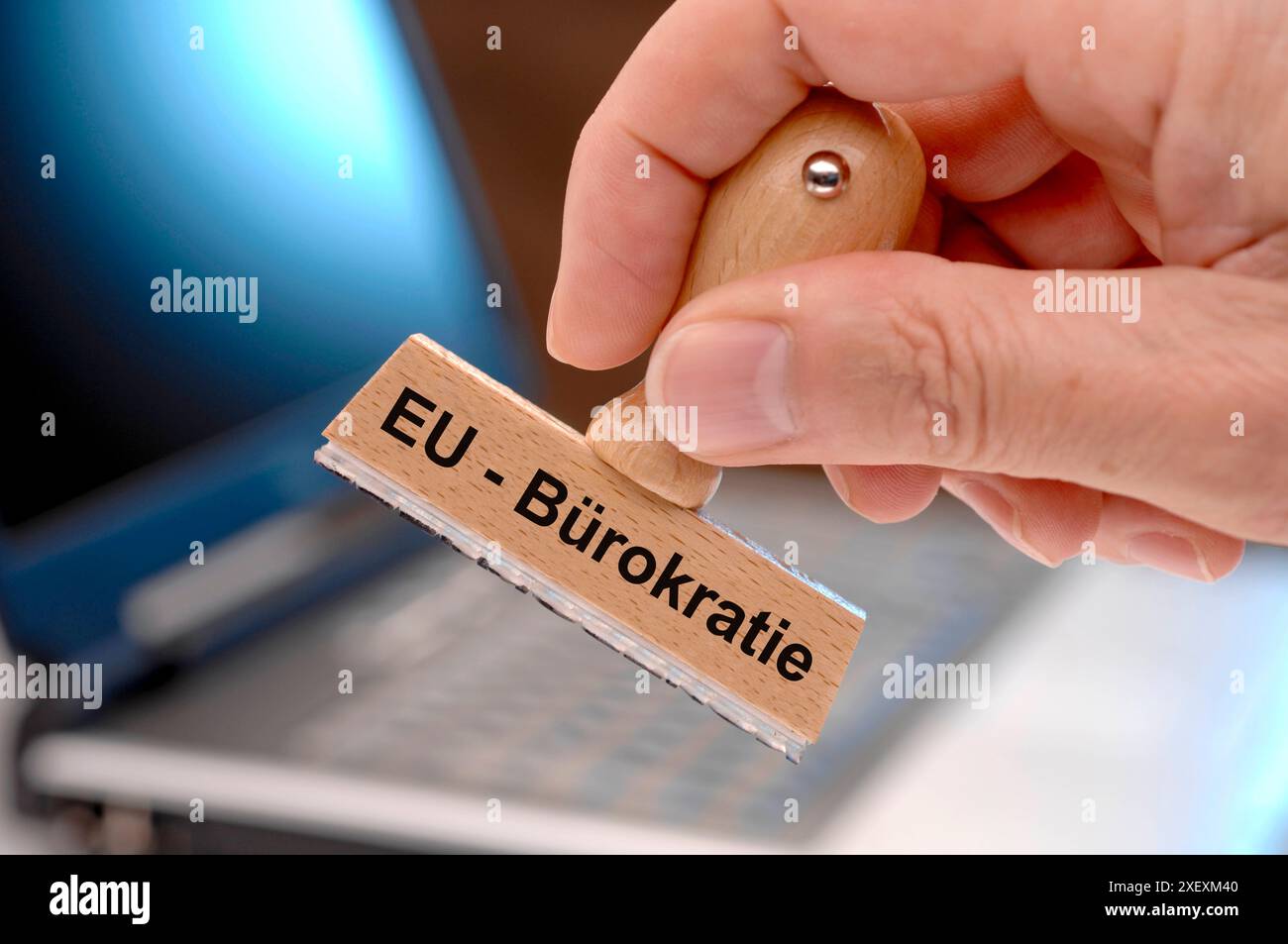 EU-Bürokratie Eine Hand hält einen Holzstempel mit der Aufschrift: EU-Bürokratie *** EU Bureaucracy A hand holds a wooden stamp with the inscription E Stock Photo