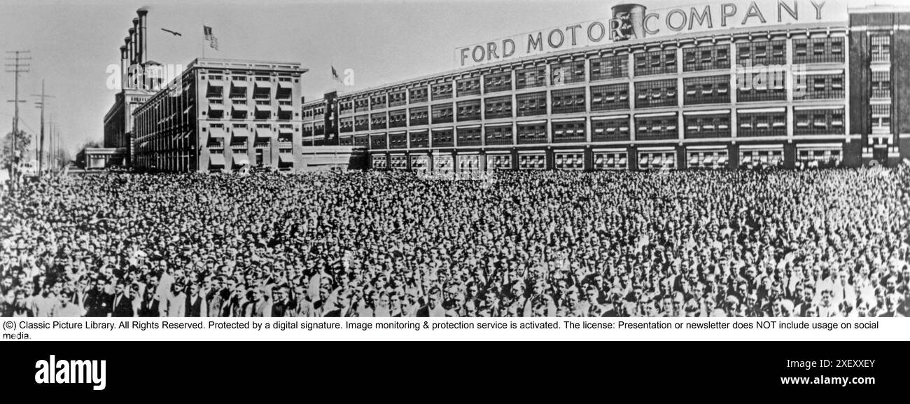 Ford history. It's factory in Highland park Michigan USA was a production facility for the Model T car and has become known for being the first factory in history to assemble cars on a moving assembly line. Picture shows the factory building and chassis in mass outside it.  1916 Stock Photo
