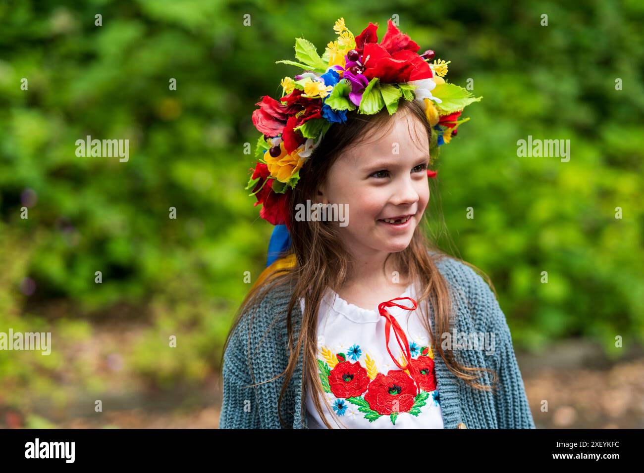 a-happy-little-girl-adorned-in-a-ukrainian-wreath-and-embroidered-shirt-grins-widely-outdoors-on-a-warm-summer-day-2XEYKFC.jpg