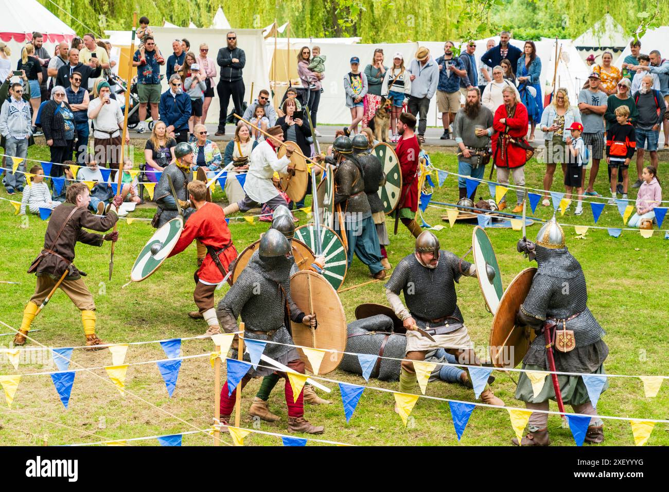 Mock battle with with two groups knights fighting each other in roped off area on the green at Sandwich during a medieval reenactment event. Stock Photo