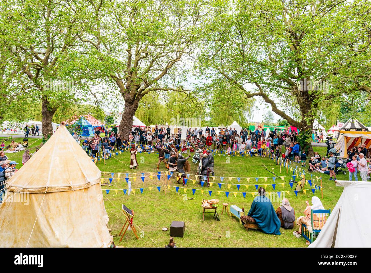 Mock battle with with two groups knights fighting each other in roped off area on the green at Sandwich during a medieval reenactment event. Stock Photo