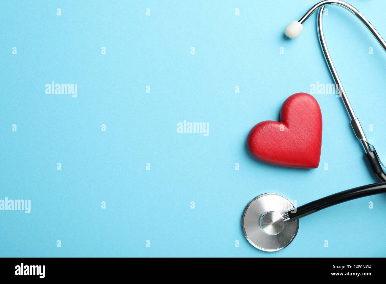 Stethoscope and red heart on light blue background, top view. Space for ...