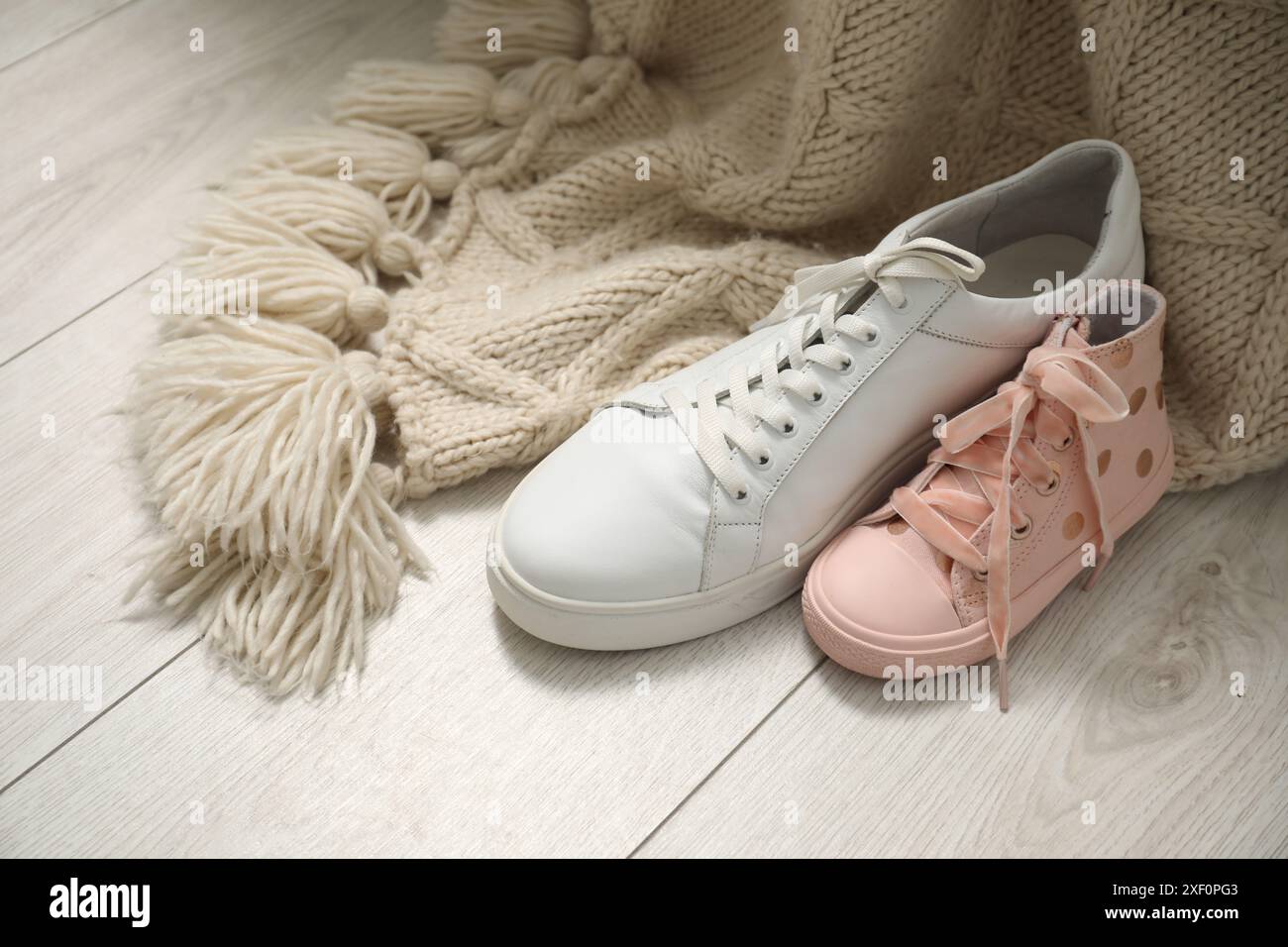 Big and small sneakers on wooden floor Stock Photo - Alamy
