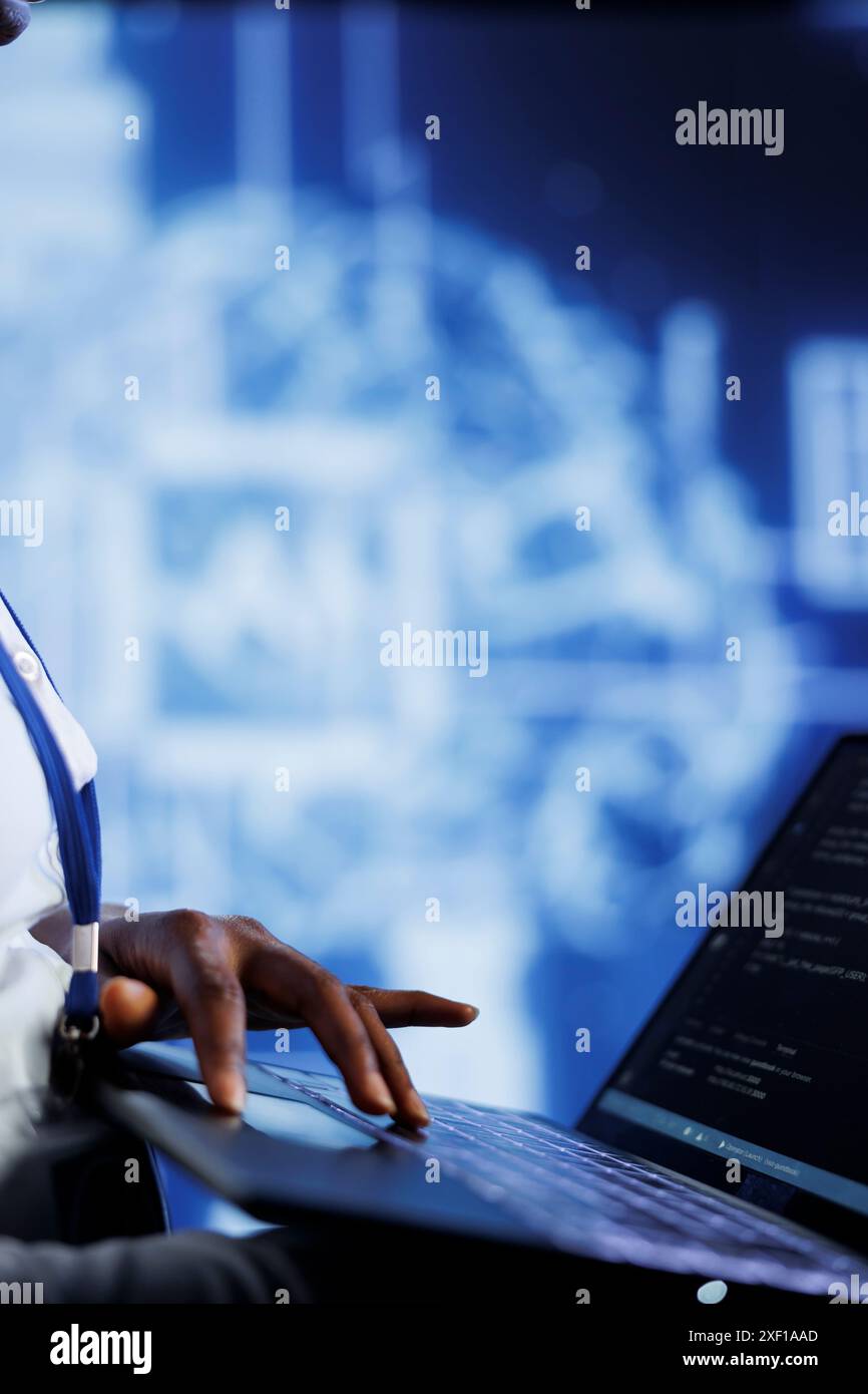 System administrator writes code on laptop to visualize artificial intelligence neural networks using augmented reality, close up. High tech facility worker runs AI script for information processing Stock Photo