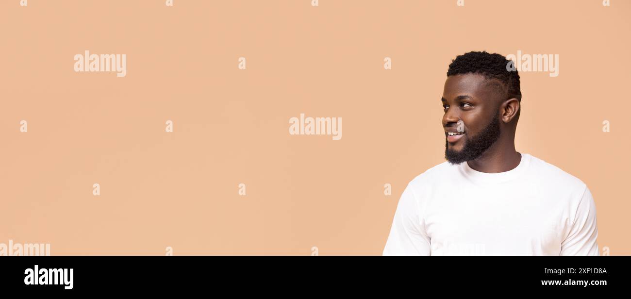 Smiling Black Man Looking Off Camera Against Light Brown Background Stock Photo