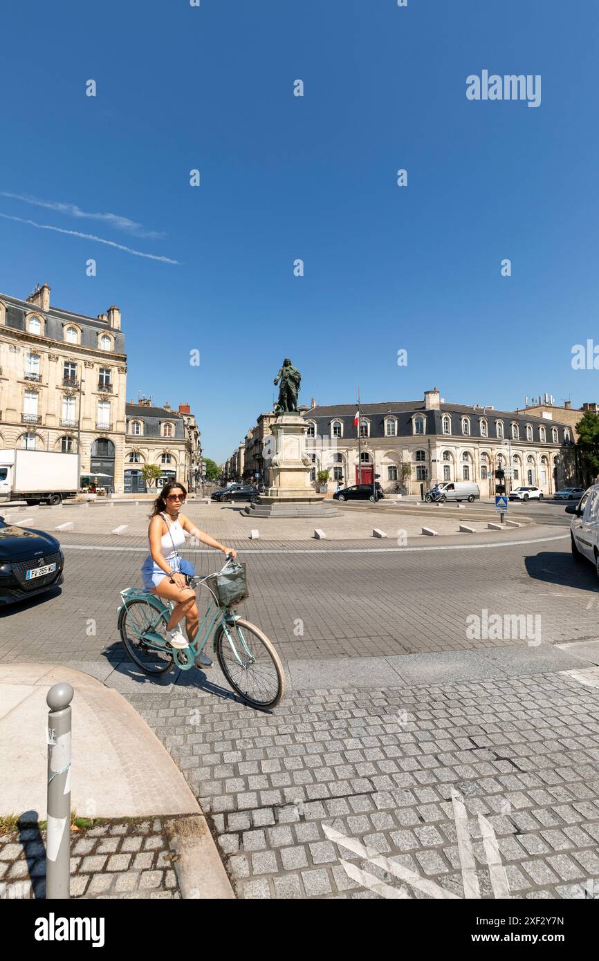 Young woman cycling on the Place du Tourny in the sun, Bordeaux, France Stock Photo