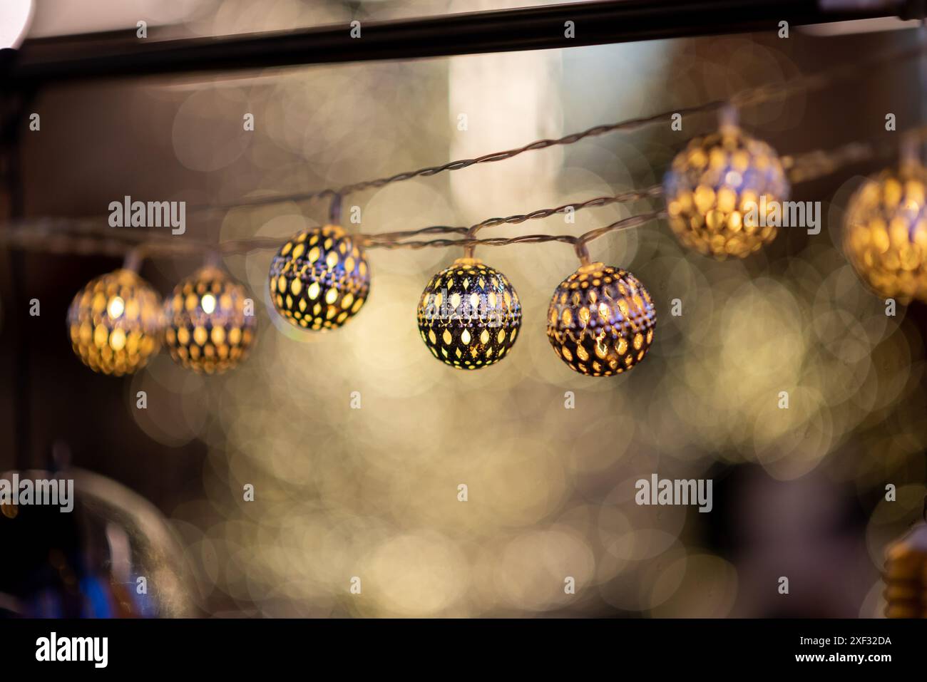 Hanging string lights with illuminated spherical bulbs against blurred background during traditional holiday Stock Photo