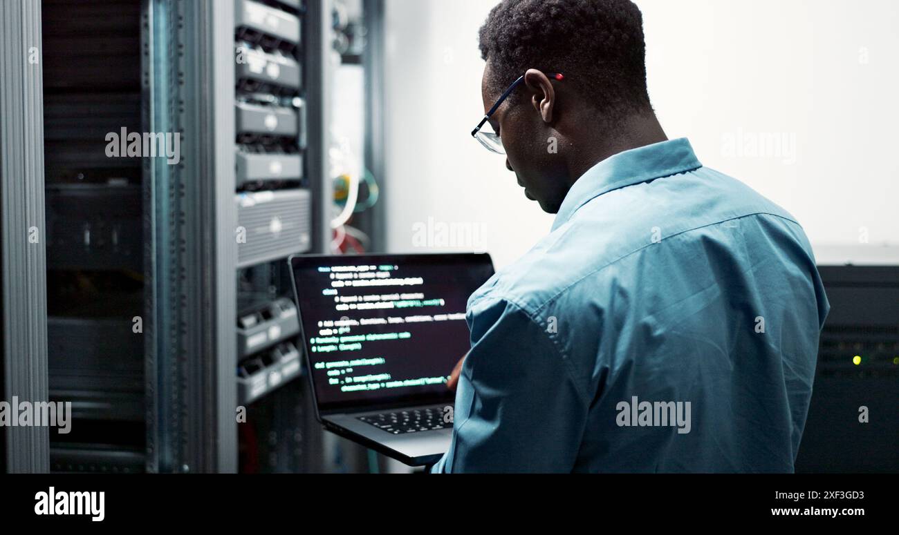 Server room, black man or coding with laptop for system upgrade, cybersecurity or screen. Software management, data or male programmer with digital Stock Photo