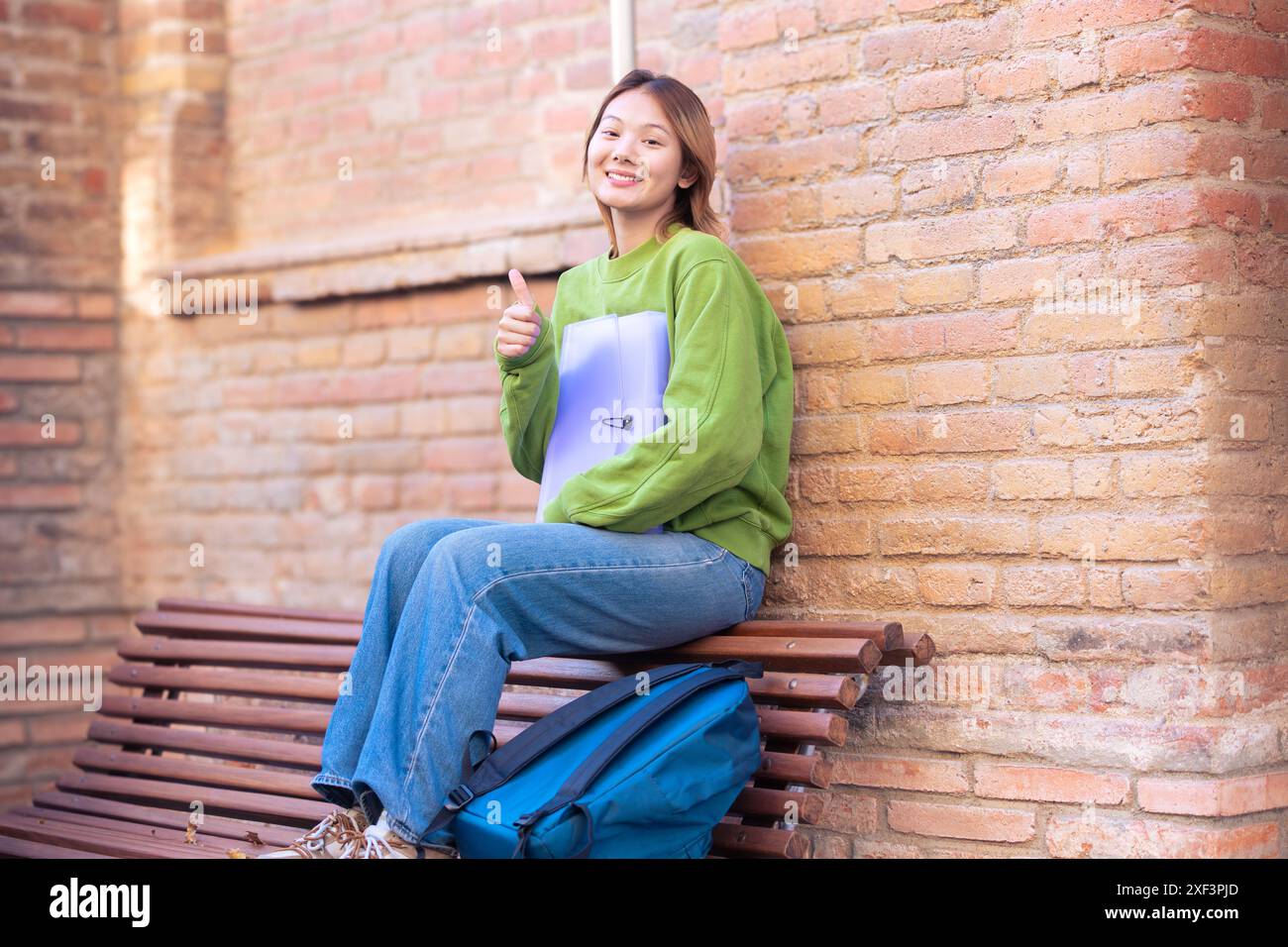 Portrait of a happy young chinese woman with a notebook outdoors. Stock Photo