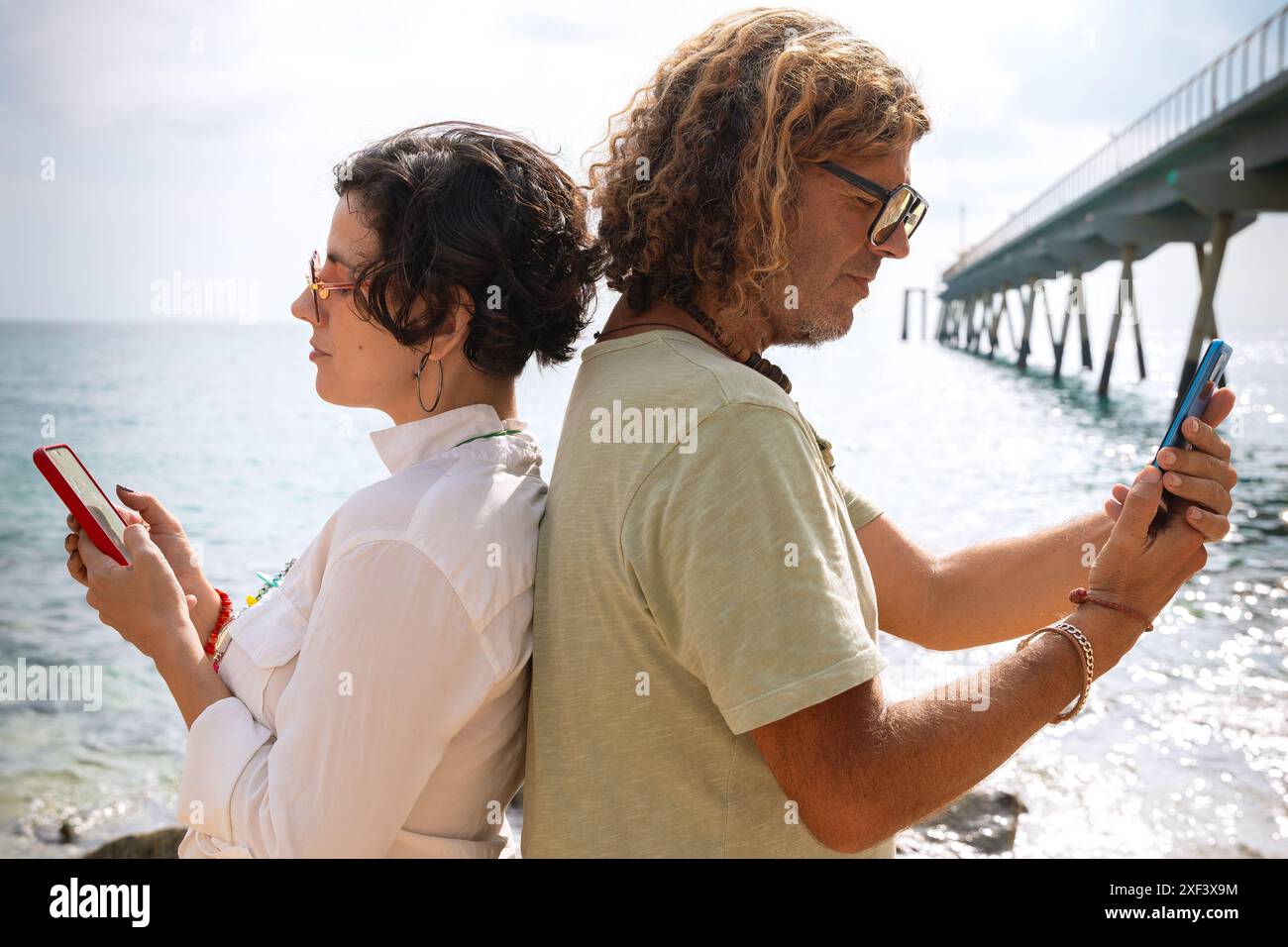 couple on the beach browsing smartphones apps. Stock Photo