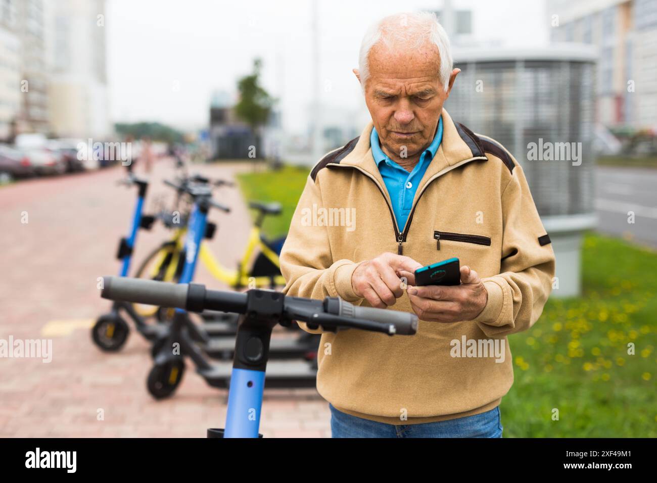 Old man using smartphone to activate e-scooter Stock Photo