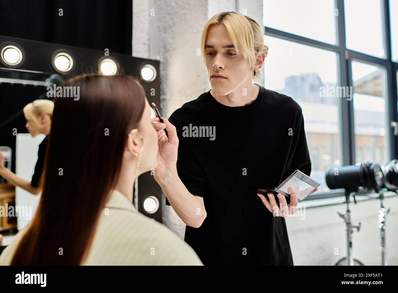 Woman getting makeup done by professional artist in front of mirror. Stock Photo