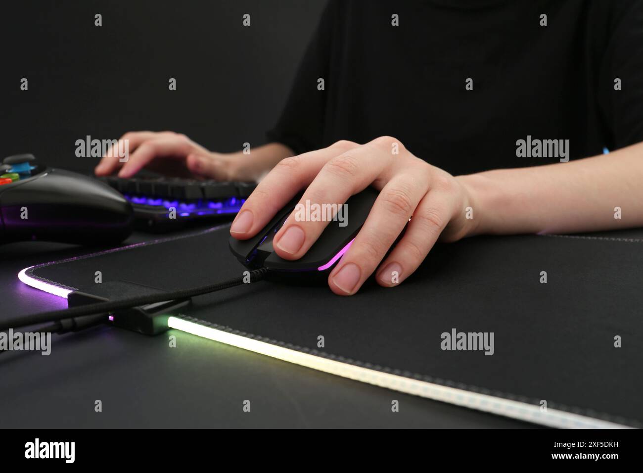 Gamer using modern wired computer mouse at dark table, closeup Stock Photo