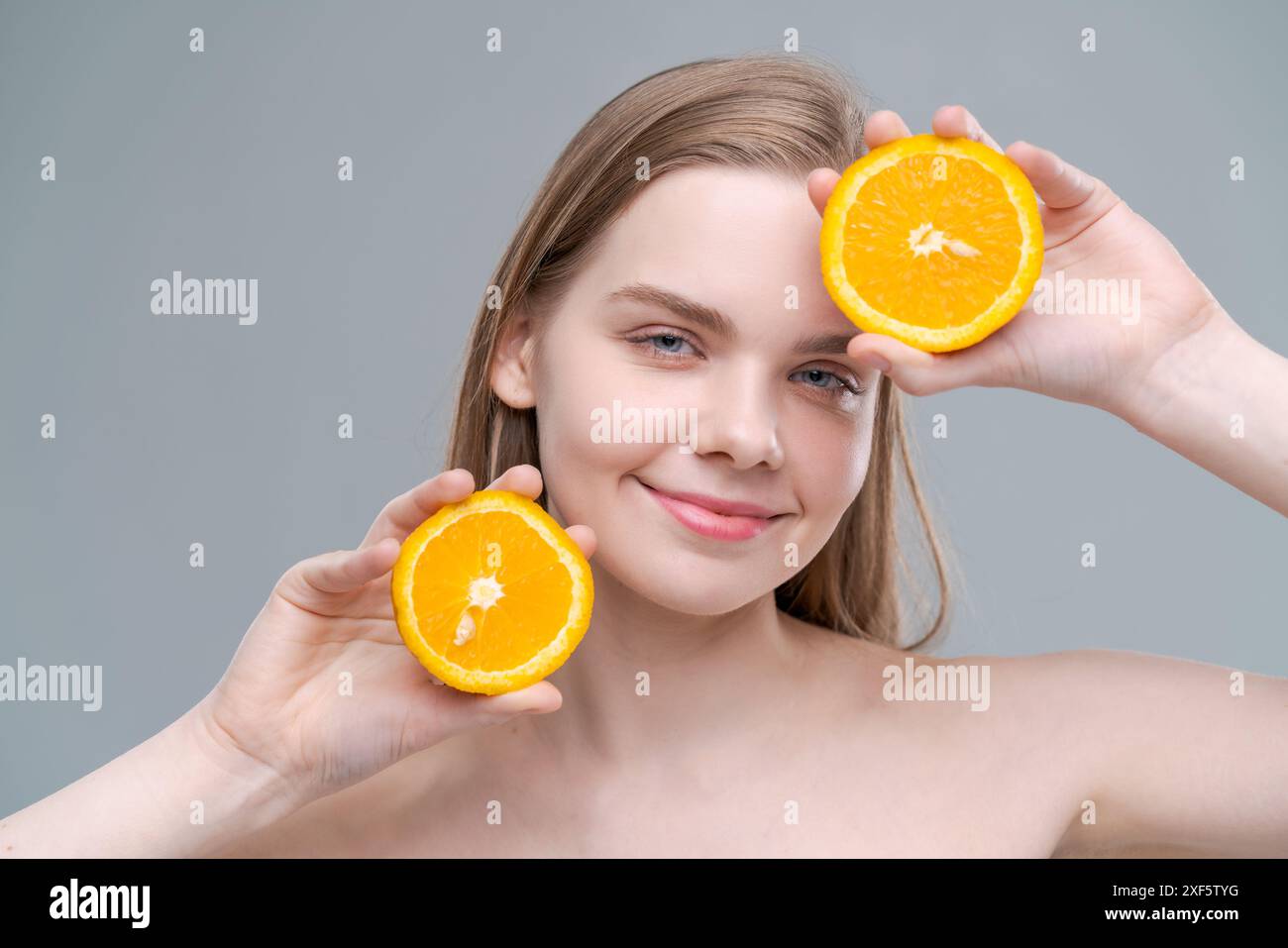 A woman is holding two oranges in her hands and smiling. Concept of ...