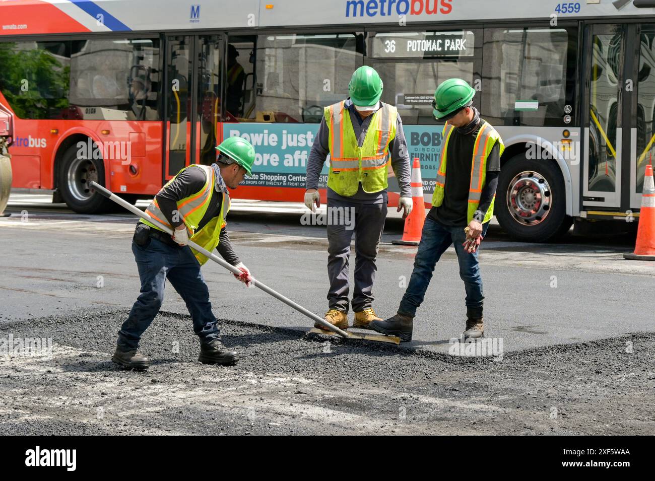 Washington DC, USA - 30 May 2024: Construction workers raking tarmac for resurfacing work on a road in downtown Washington DC Stock Photo