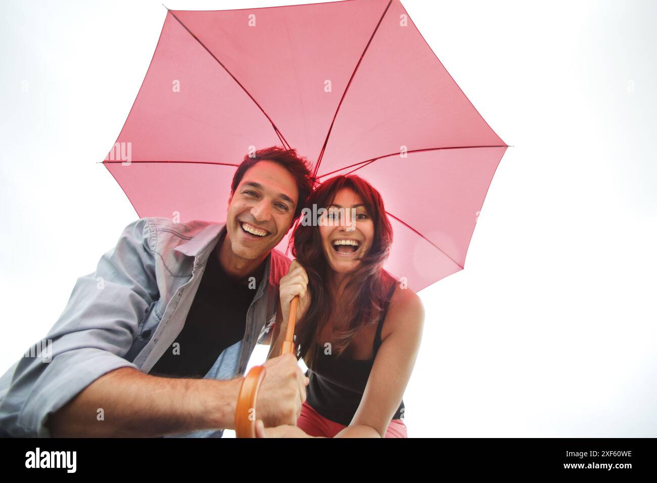 Couple in their 30´s smiling under umbrella Stock Photo - Alamy