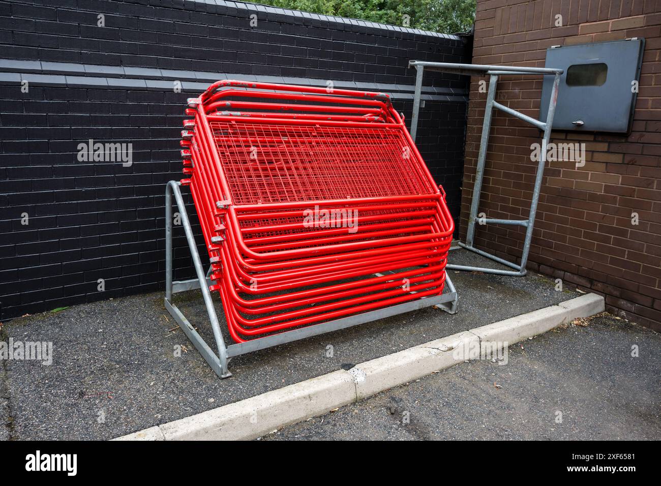 Stack of red metal barriers neatly arranged on a rack against a black ...