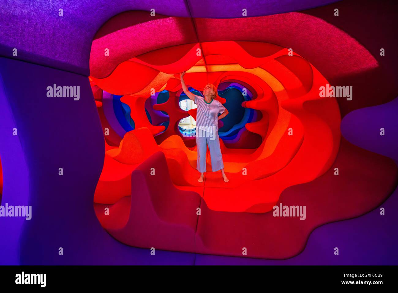 A visitor reaches up to touch the curved inner wall of the walk-in installation for the special exhibition "Fascination of Caves" at the Paula Modersohn-Becker Museum in Bremen. Ansgari-Viertel, Bremen, Germany. Stock Photo