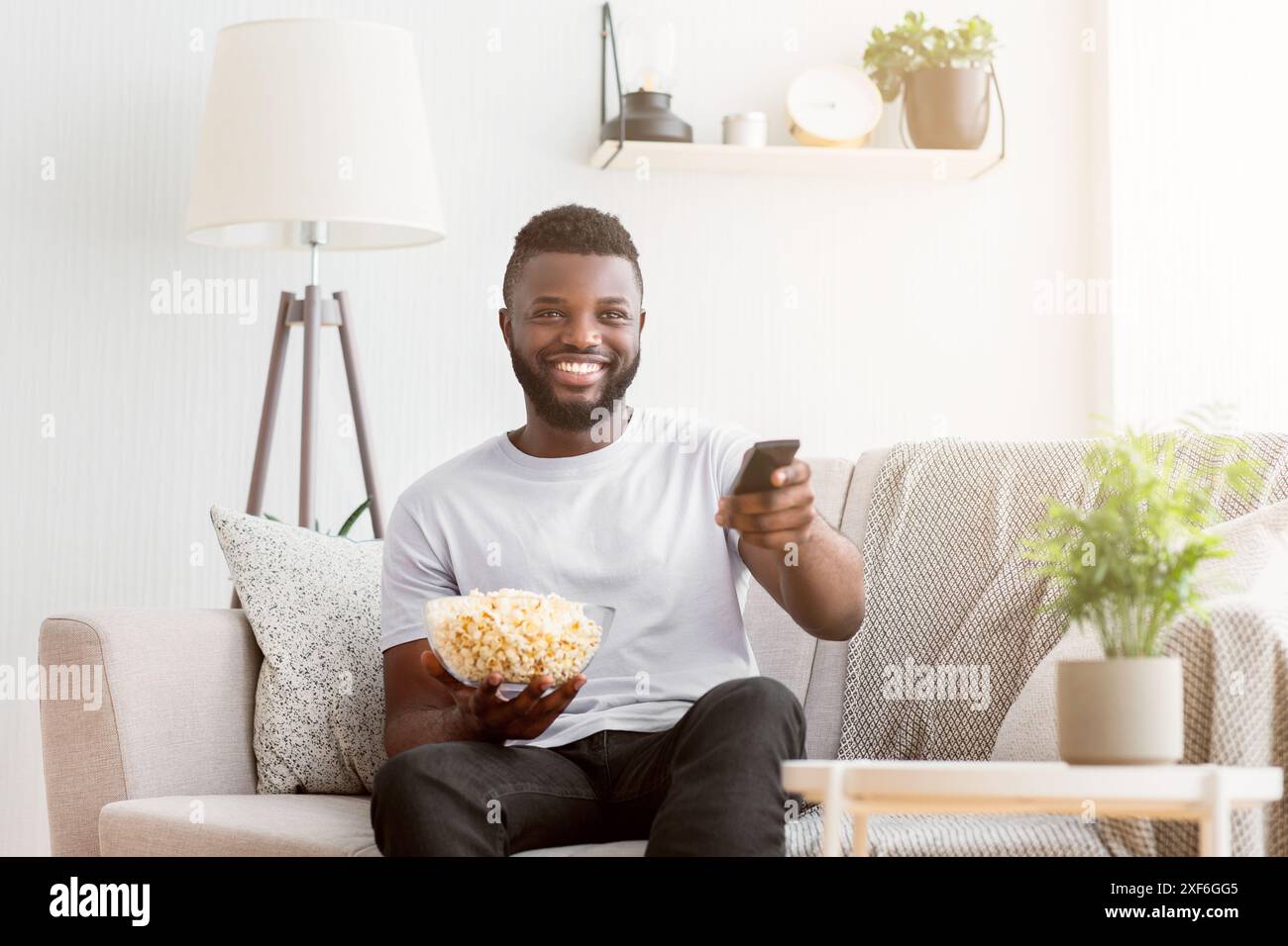 Man Relaxing on Couch With Remote and Popcorn Stock Photo
