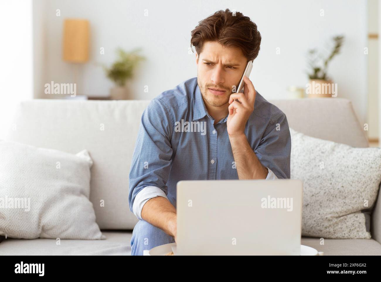 Man on Phone Call Working on Laptop at Home Stock Photo