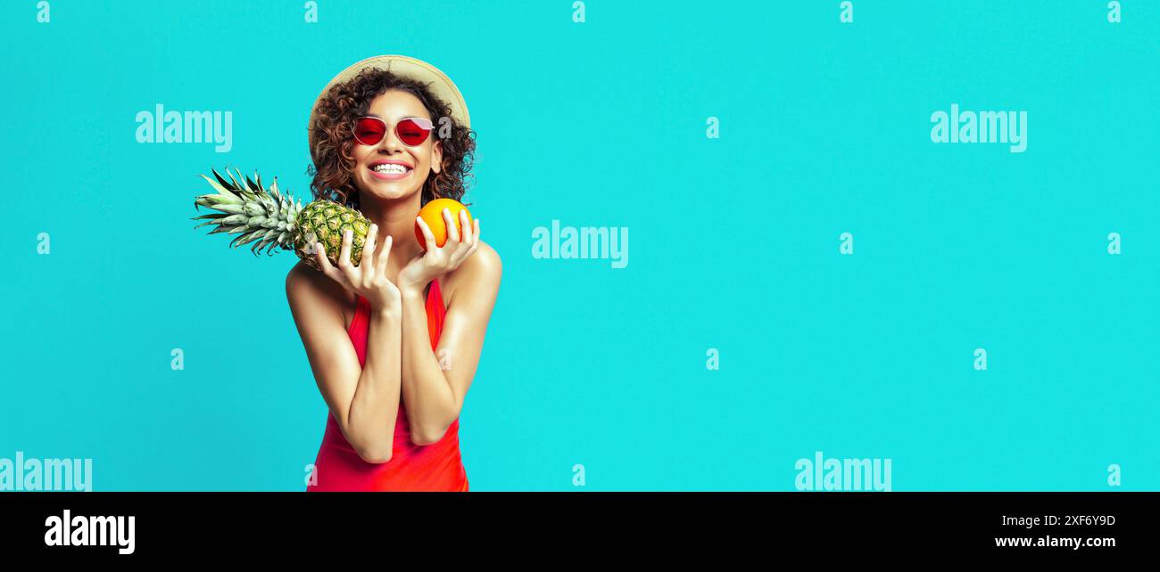 Smiling Woman Holding Pineapple and Orange on Blue Background Stock Photo