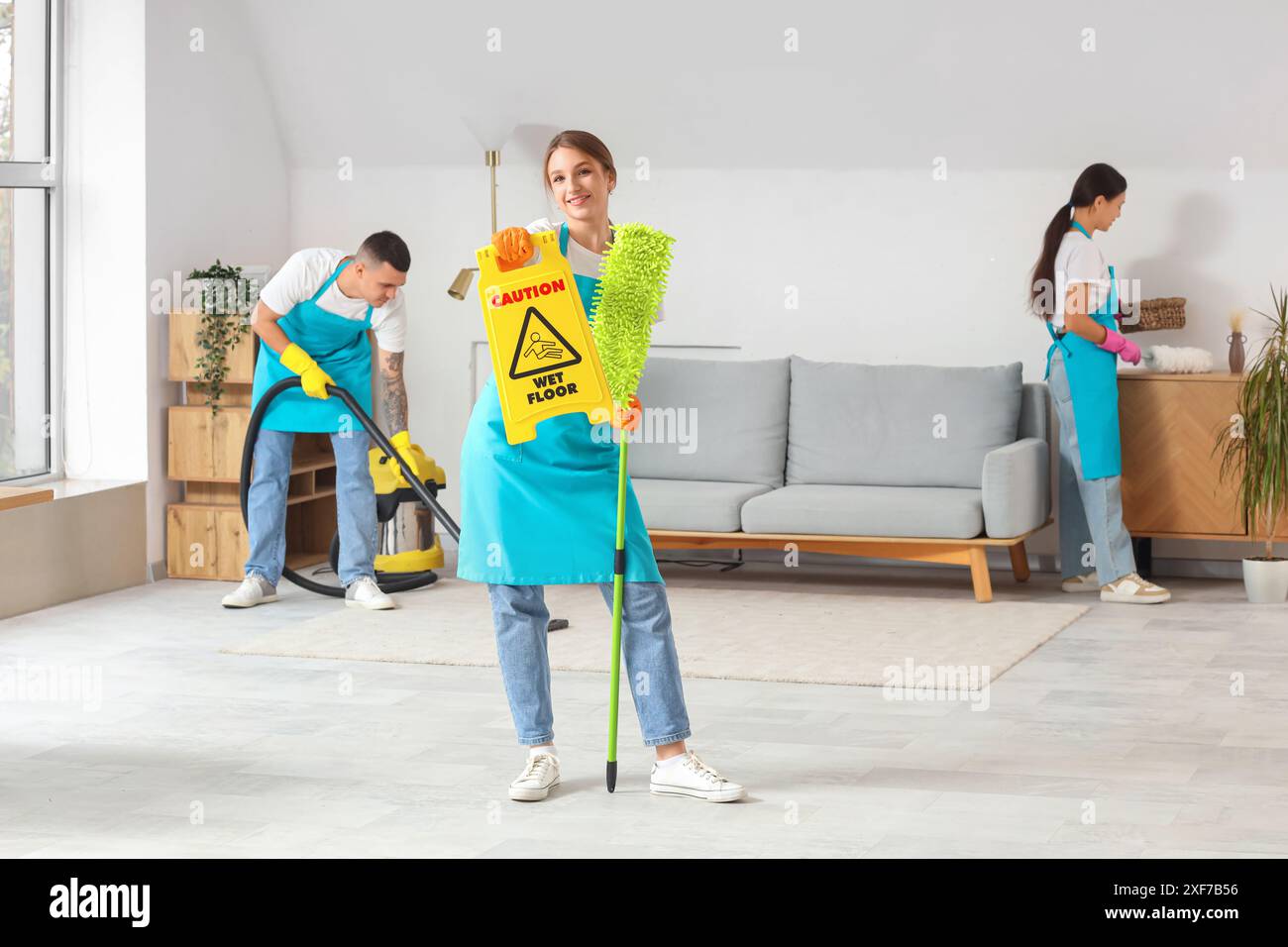 Female janitor with caution sign and mop in room Stock Photo - Alamy