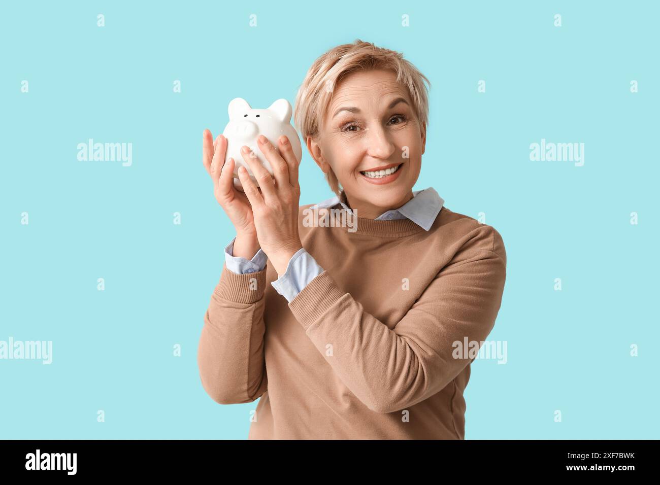 Happy mature woman with white piggy bank on blue background Stock Photo ...