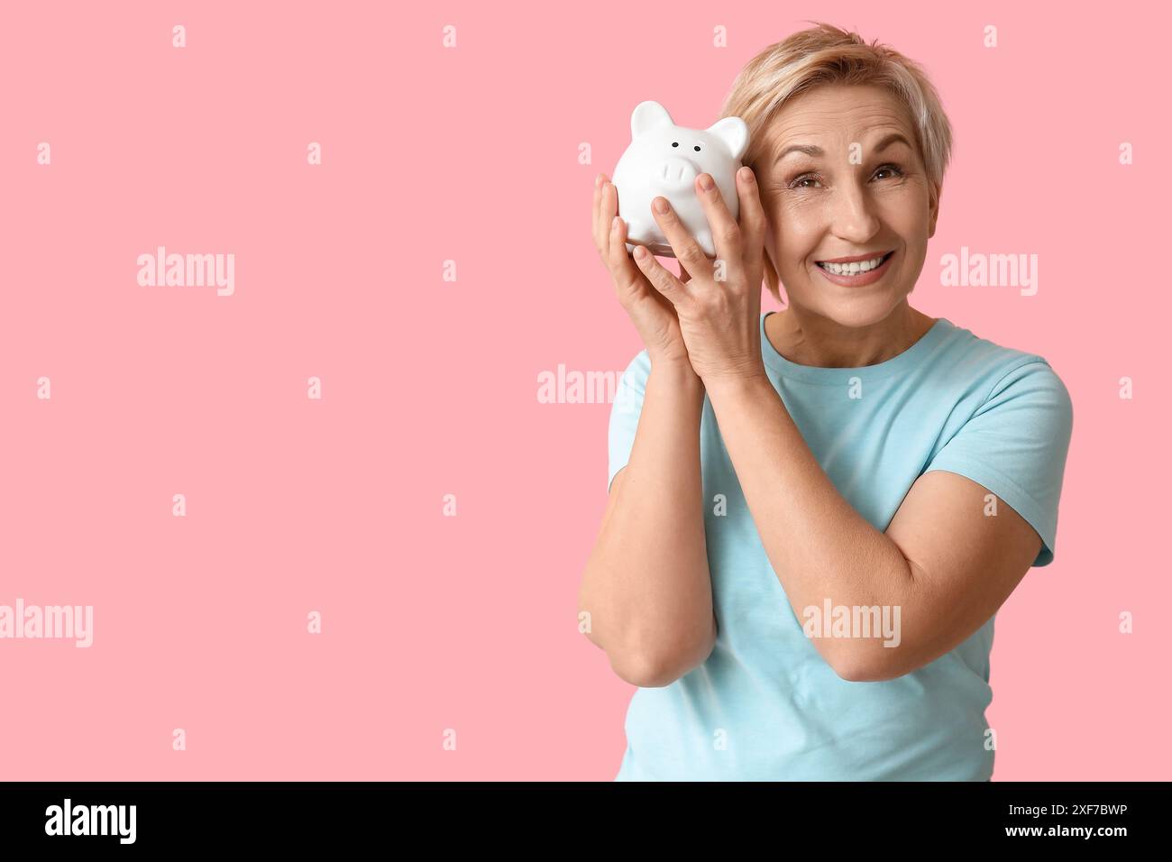 Happy mature woman with white piggy bank on pink background Stock Photo ...
