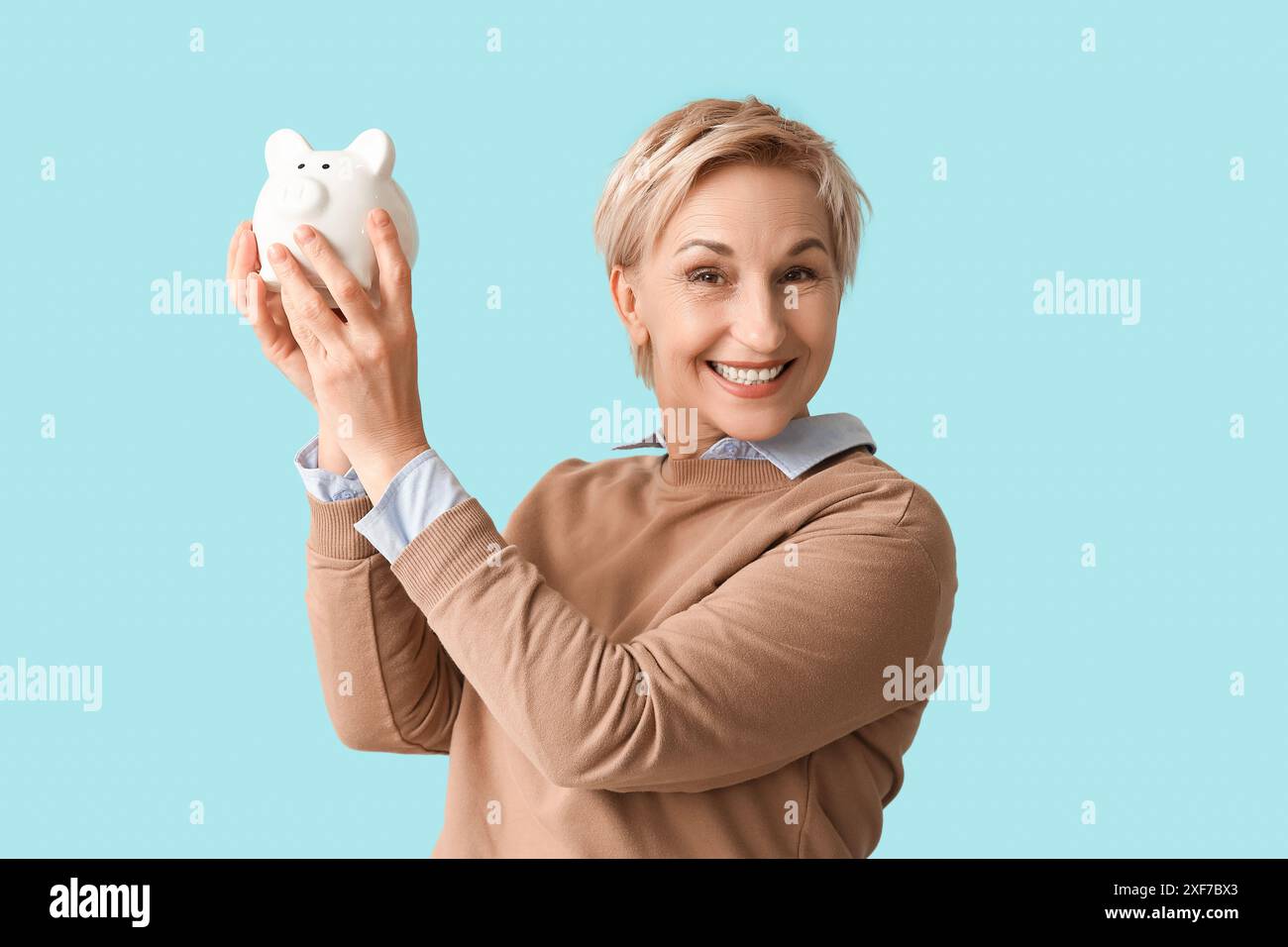 Happy mature woman with white piggy bank on blue background Stock Photo ...