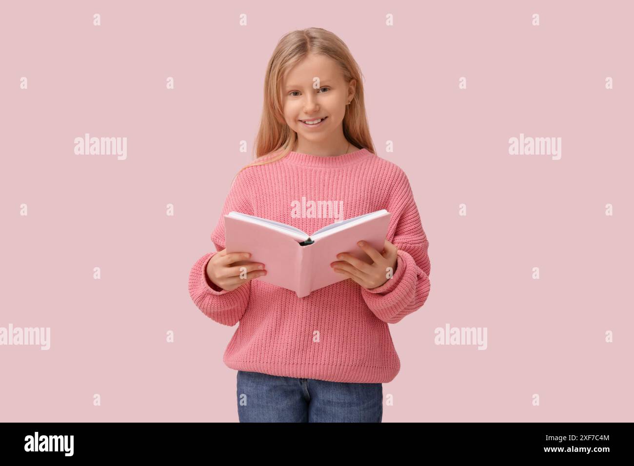 Cute little girl with book on pink background Stock Photo - Alamy