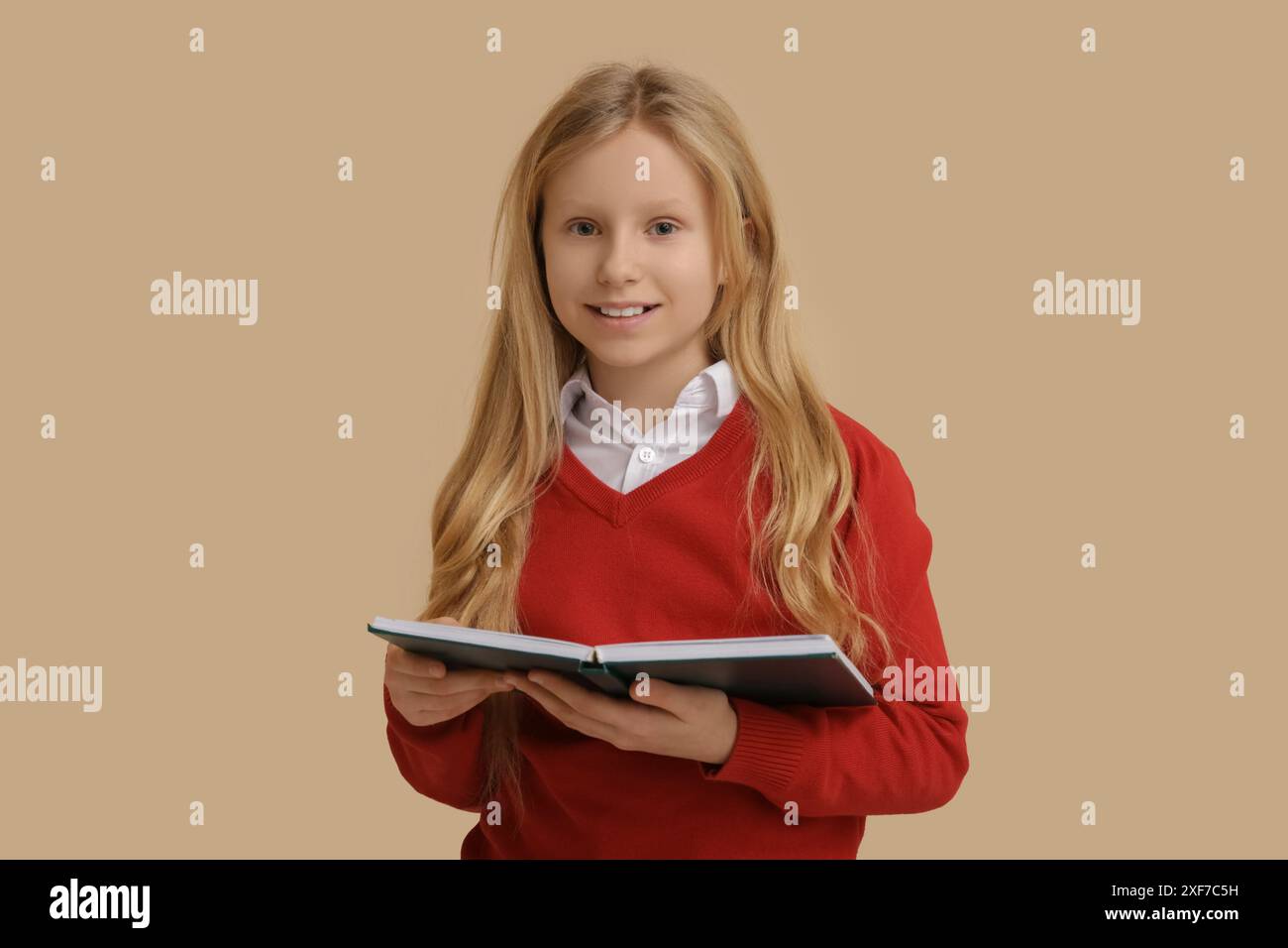 Cute little girl with book on beige background Stock Photo - Alamy