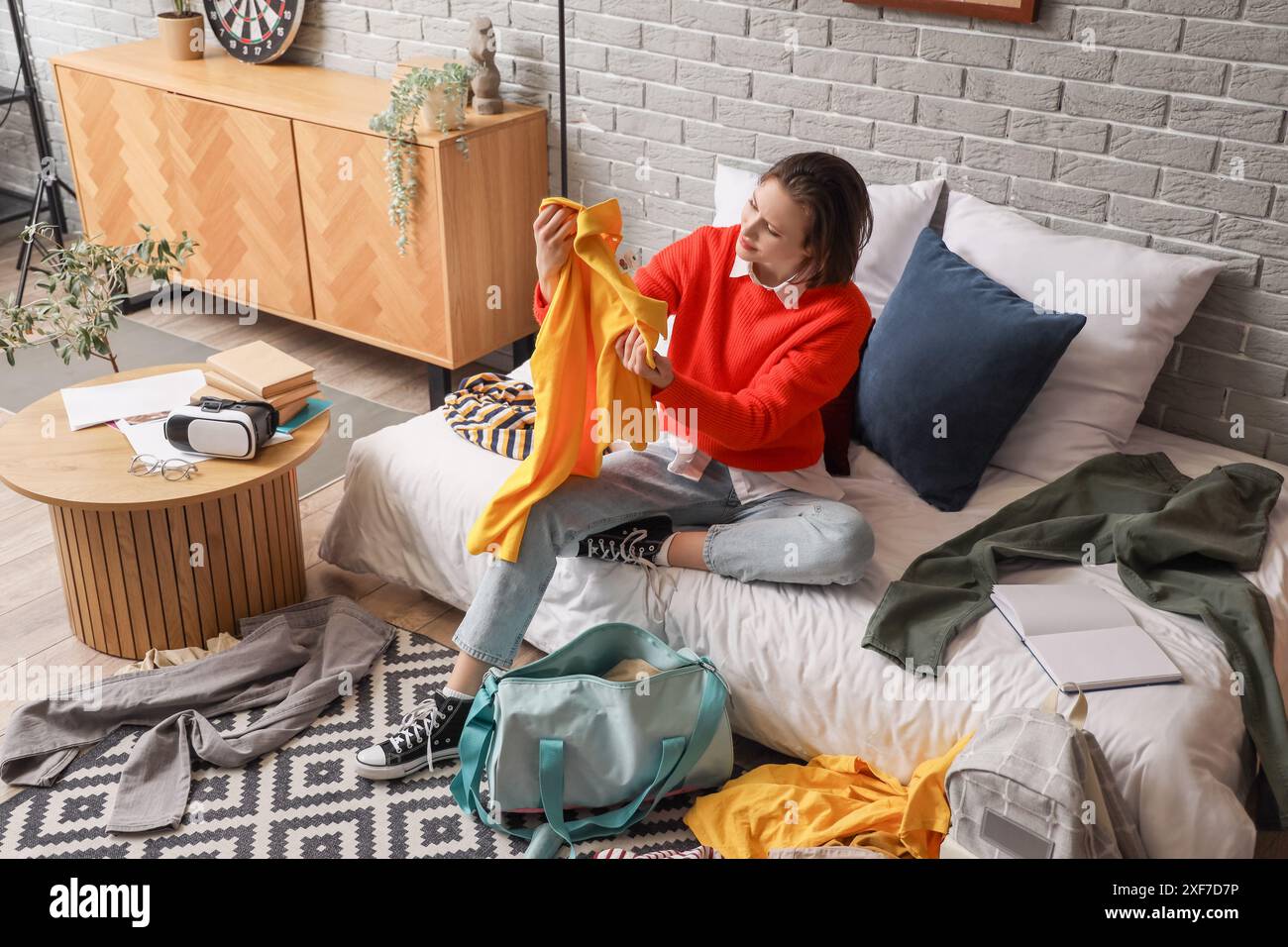 Female student with clothes sitting in messy bedroom Stock Photo - Alamy