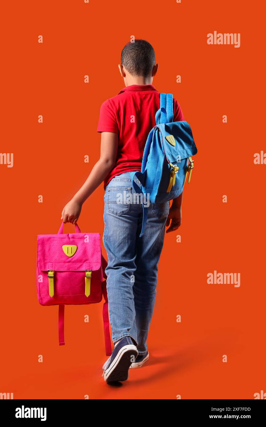Little schoolboy with backpacks on orange background, back view Stock ...