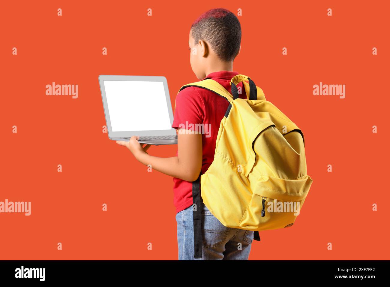 Little schoolboy with laptop and backpack on orange background, back ...
