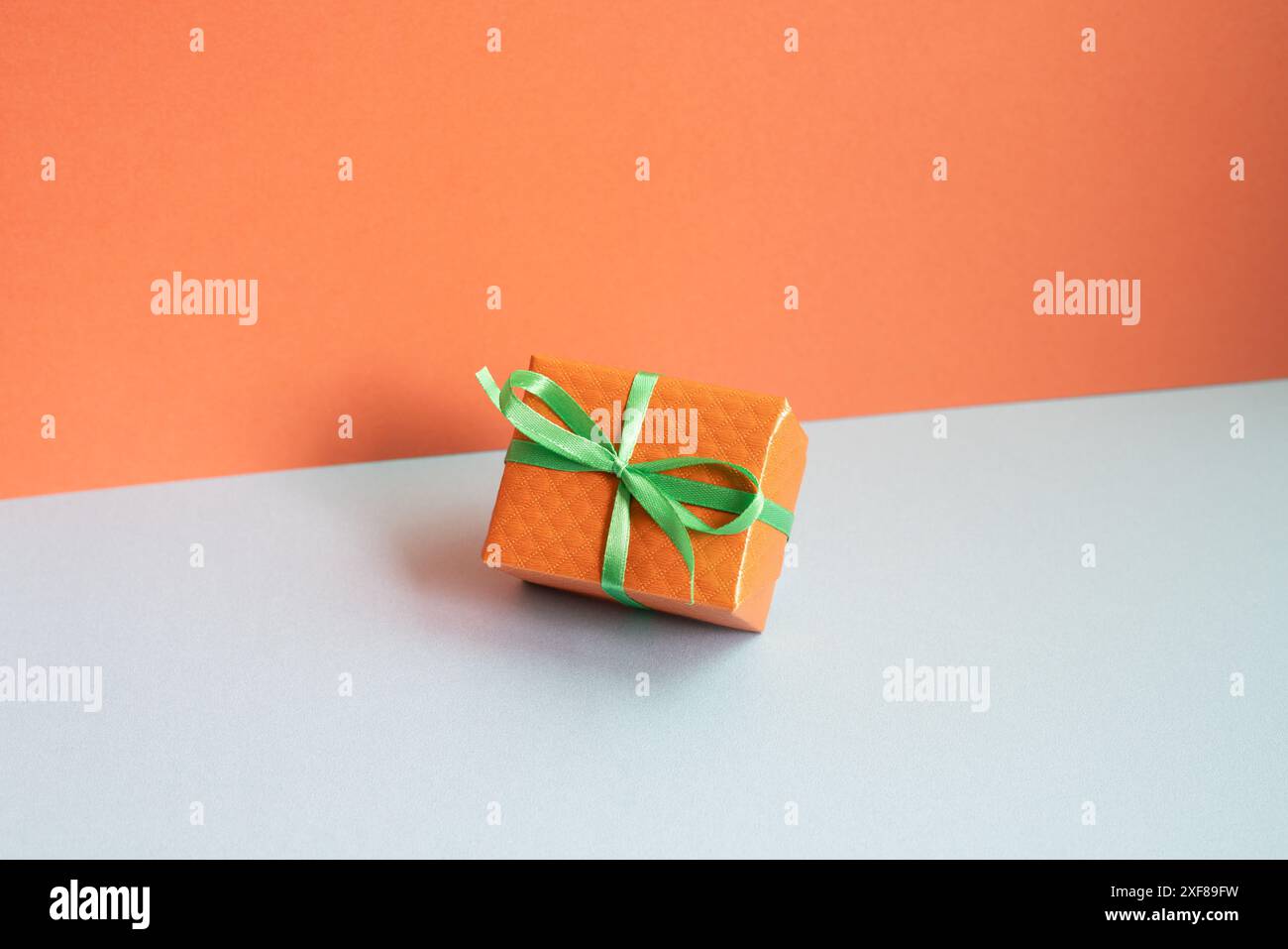 Orange gift box on gray desk. red wall background Stock Photo