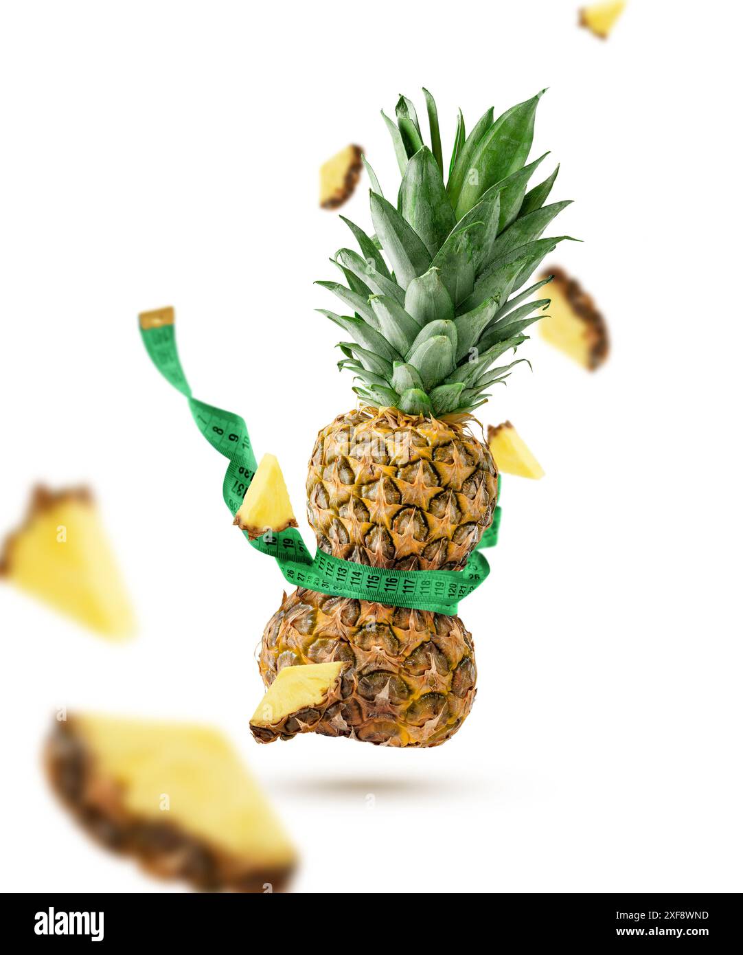 Flying tightened pineapple with measuring tape isolated on white background. Slimming concept. Stock Photo