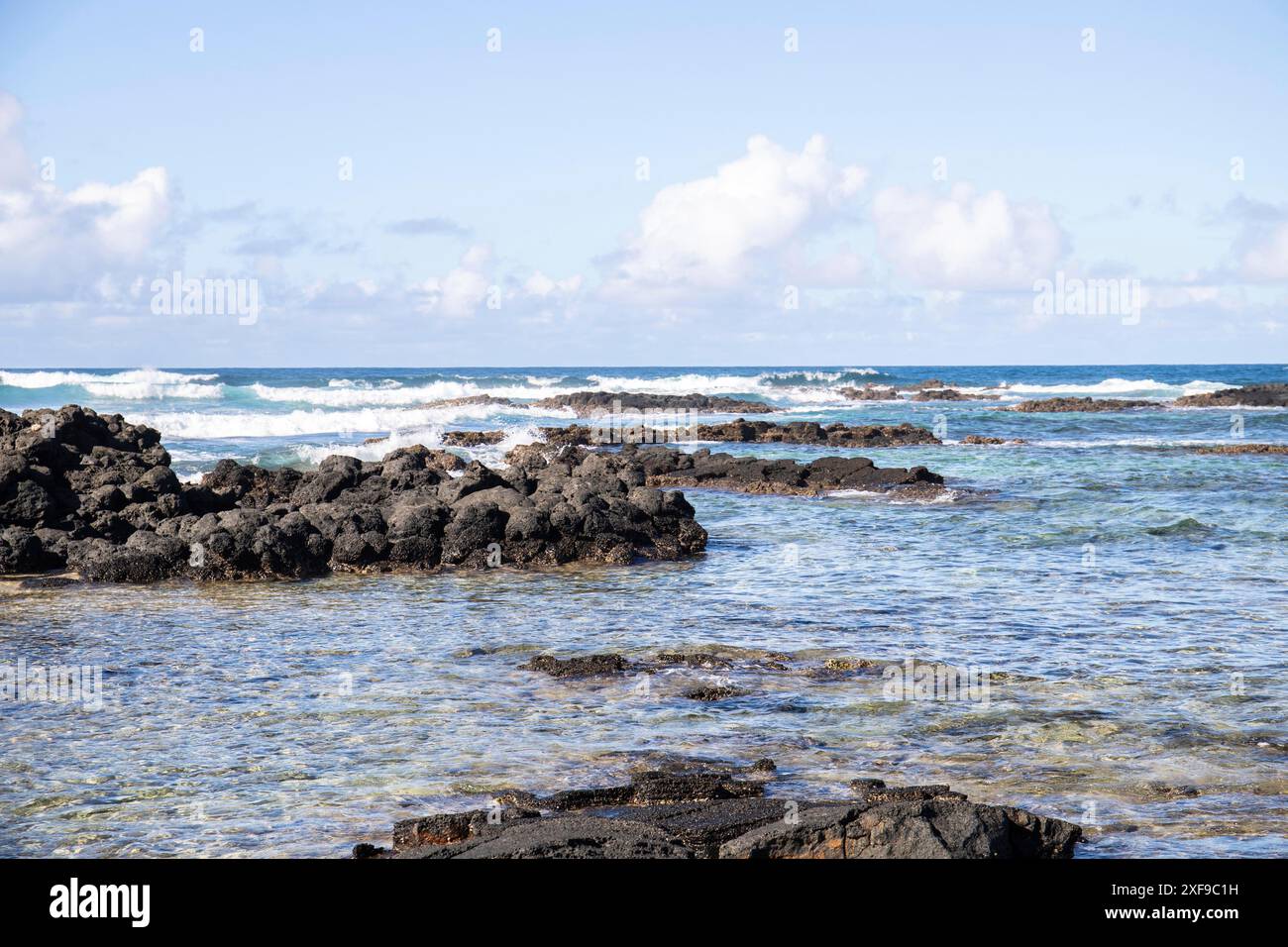 Beautiful lava beach during the day. Lava rocks alternate with crystal ...