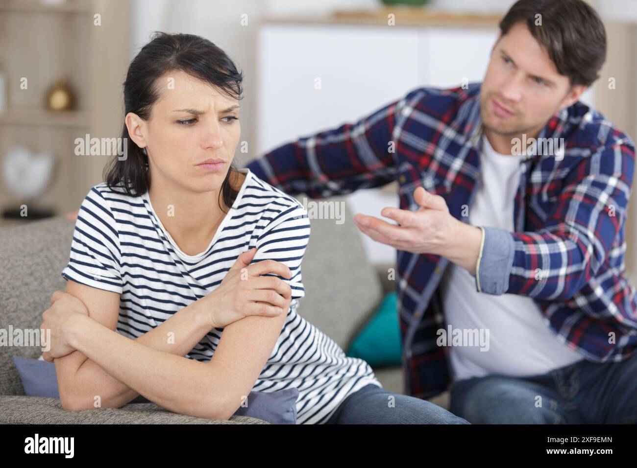 man supporting upset girlfriend while sitting together on couch Stock Photo