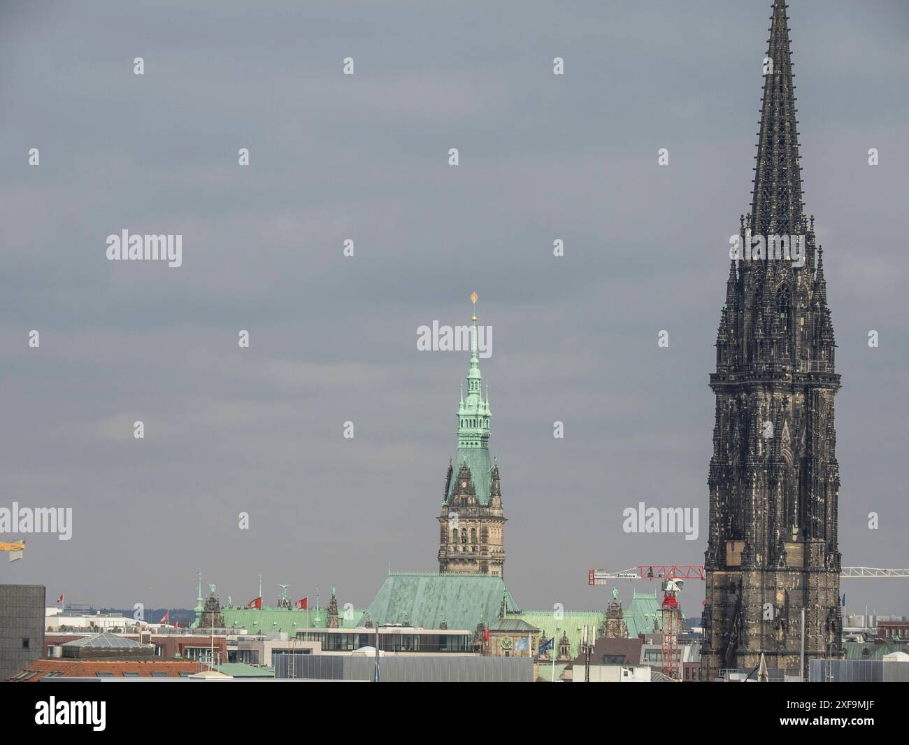 City view with a large gothic church tower and a green copper tower under a cloudy sky, hamburg, germany Stock Photo