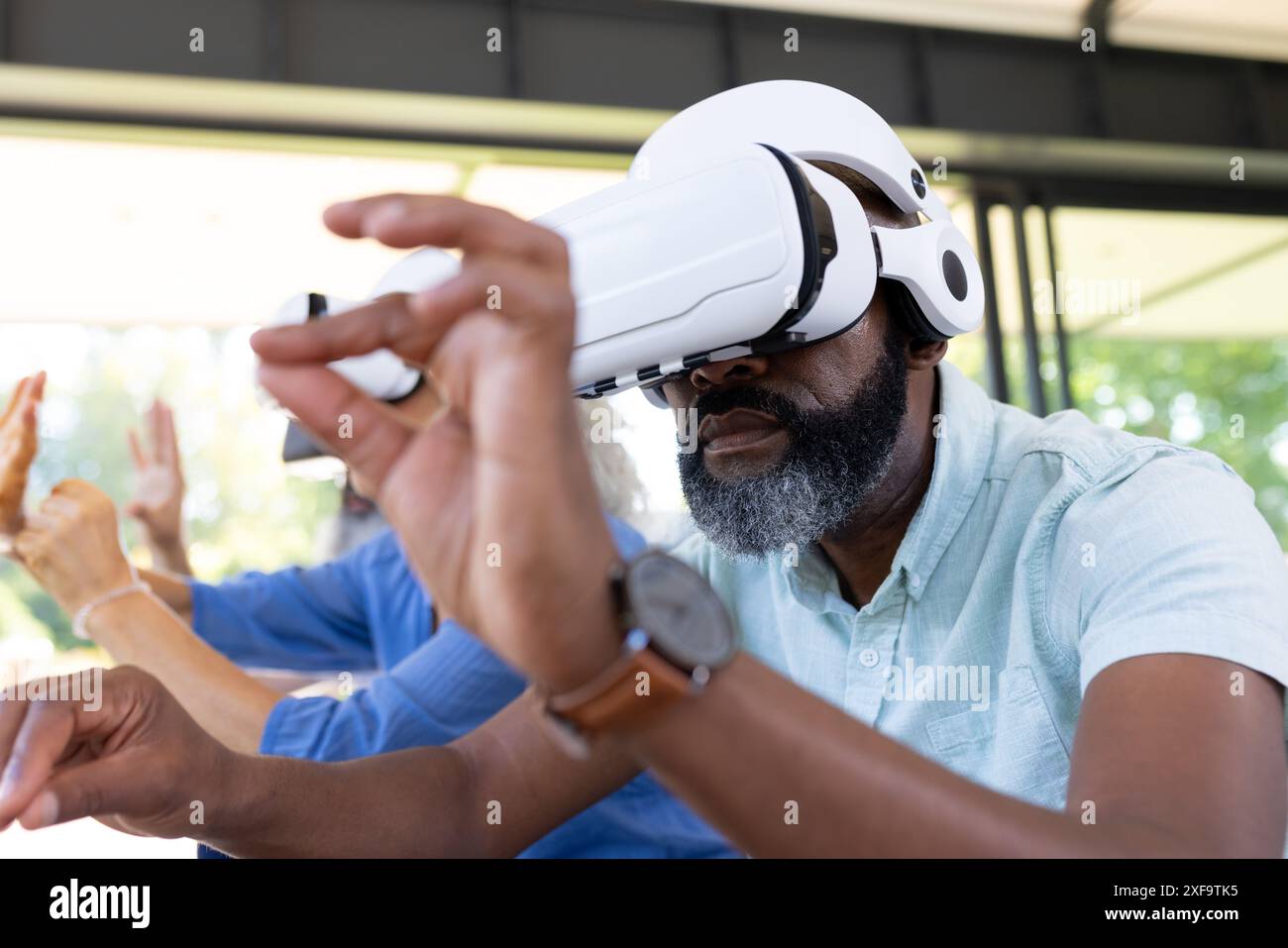 Using VR headset, senior man exploring virtual reality with friends Stock Photo