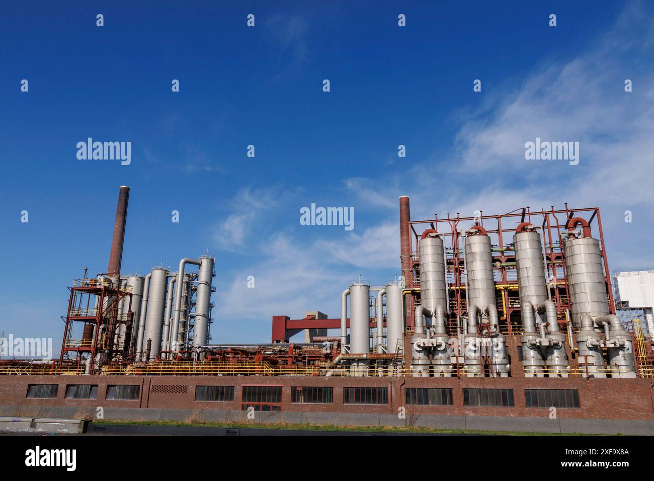 Large industrial plant with numerous metal silos and chimneys under a ...