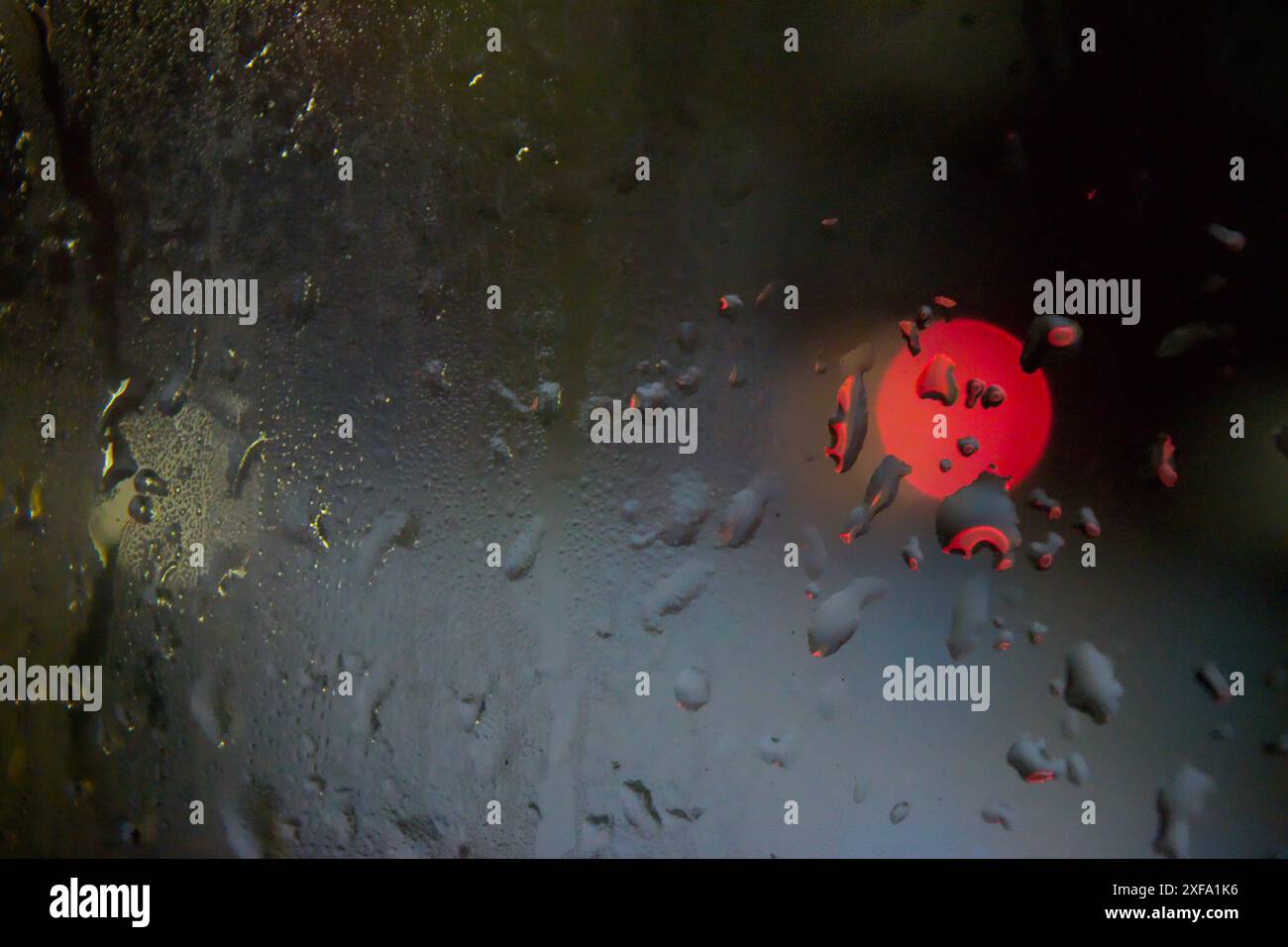 Raindrops on Window with Night Time City Lights Bokeh in Background Stock Photo