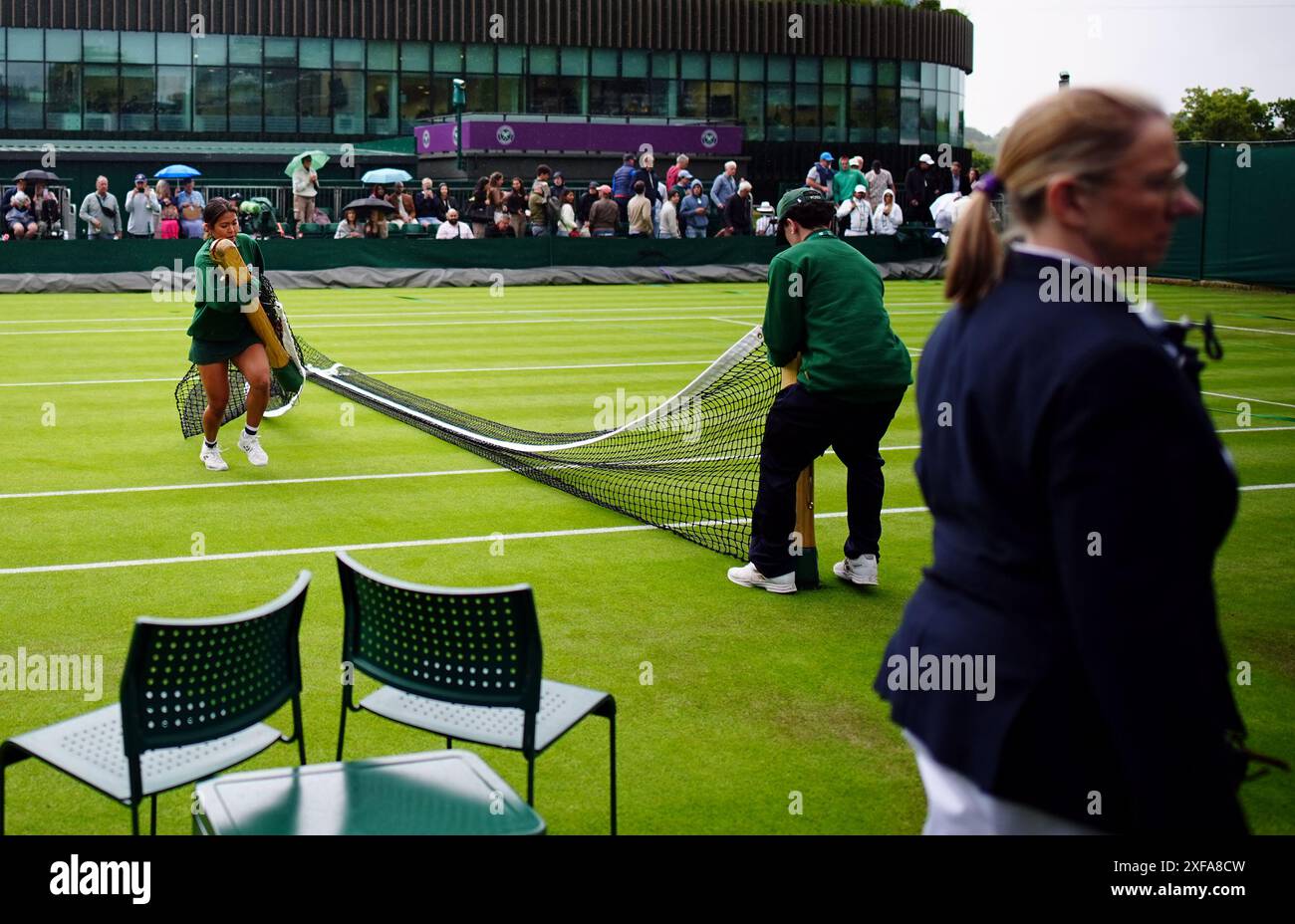 The net is removed and an outside court is covered as rain stops play ...