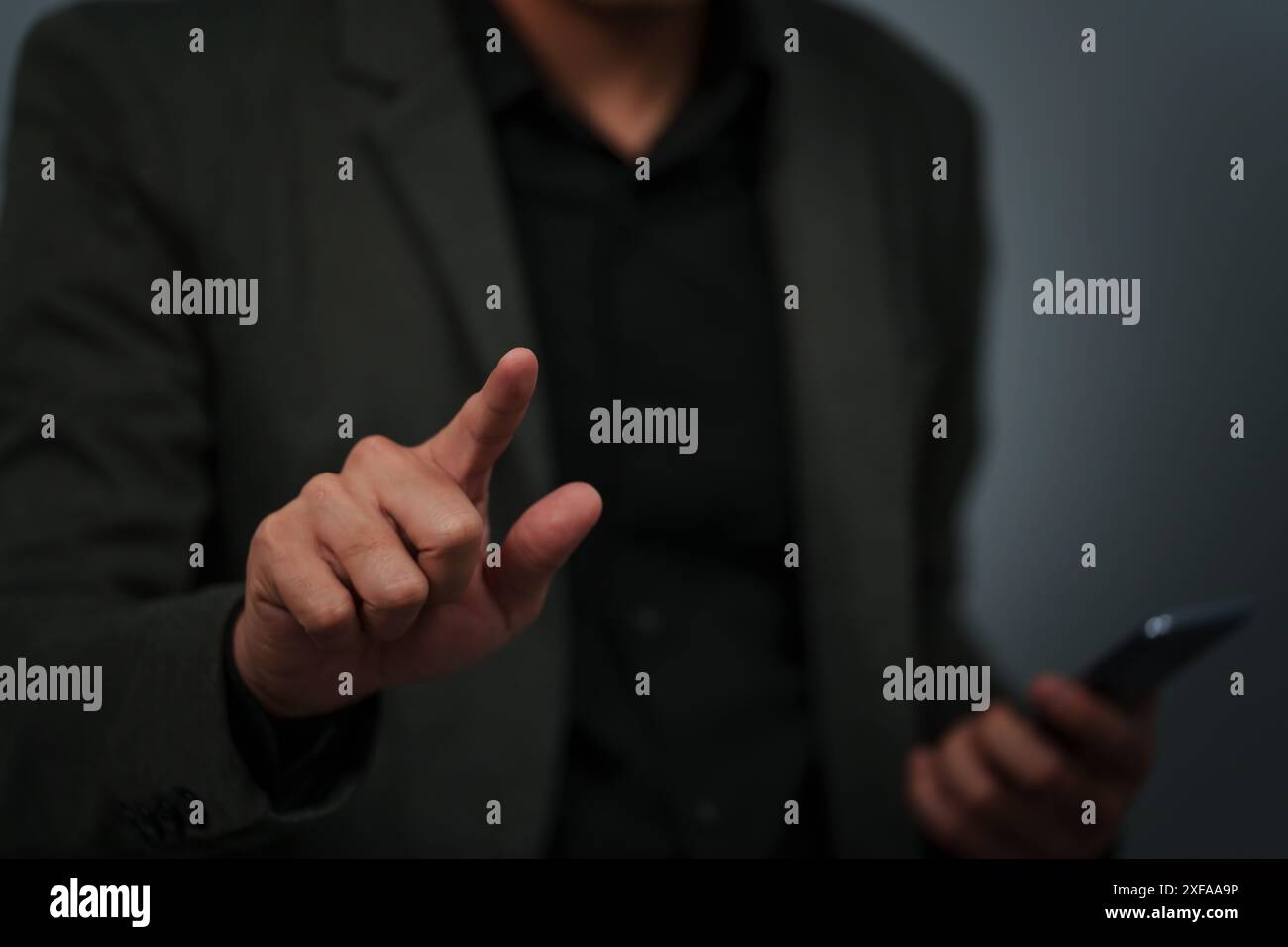 businessman is holding smartphone and pointing index finger against background Stock Photo