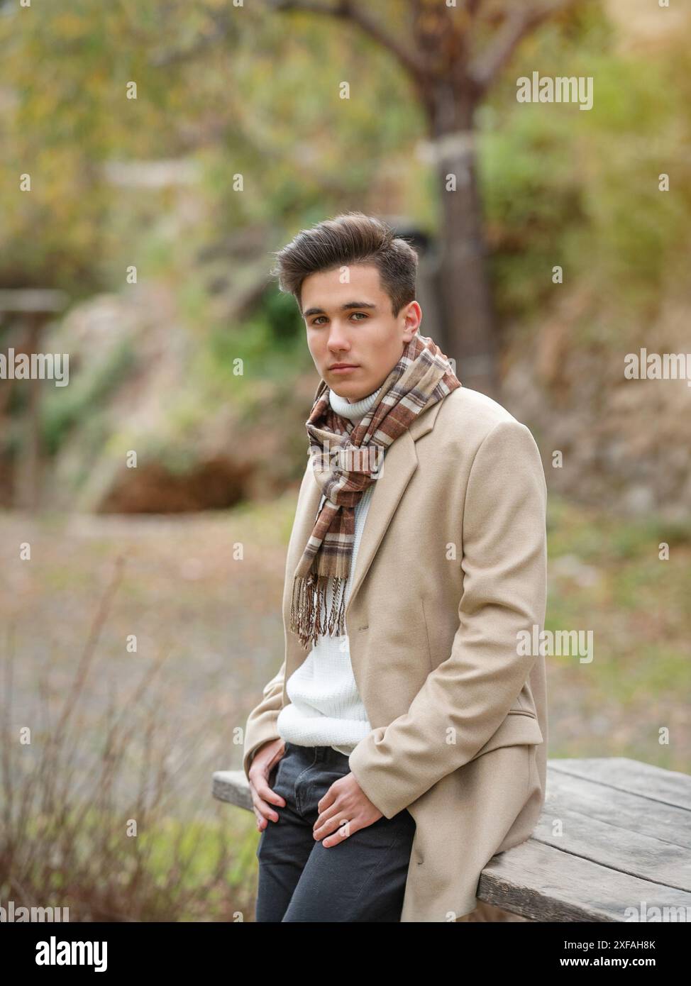 Young man wearing winter clothes in the street. Young bearded guy with modern hairstyle with coat, and white t-shirt. Stock Photo