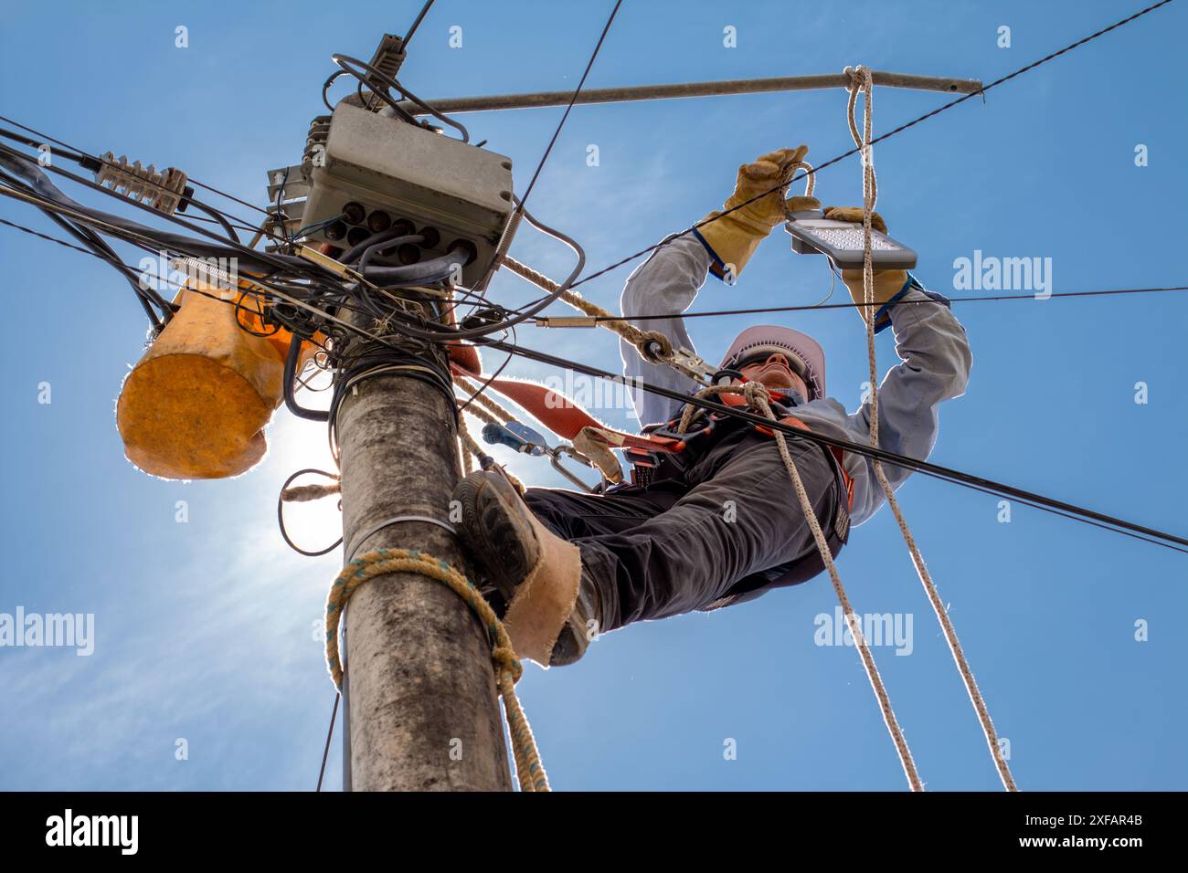 electrical technician performs maintenance to public lighting using all industrial safety elements. Stock Photo