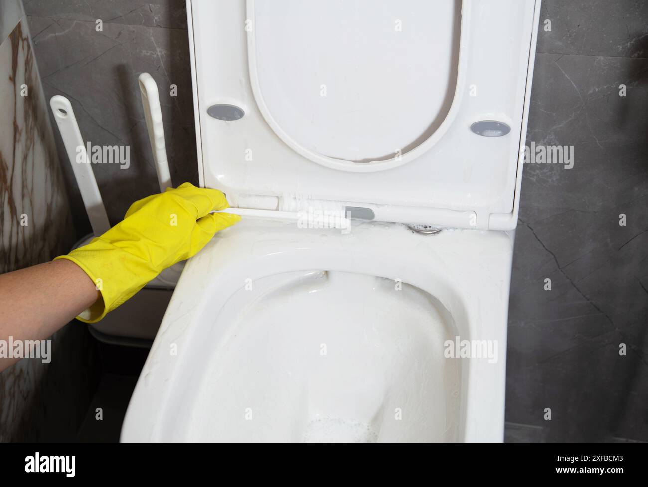 Washing and cleaning the toilet rim with a special brush with a cleaning agent to remove